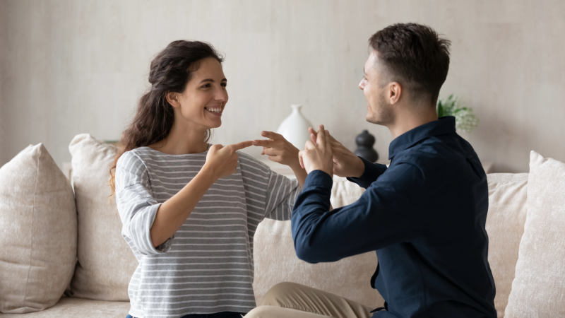Young woman practices signing with a man of equivalent age.