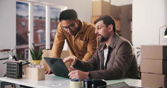 2 Men working on a computer at a desk together