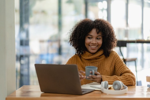 A women working on a computer while drinking coffee