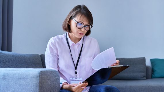 A person wearing an orange cardigan while holding a notebook