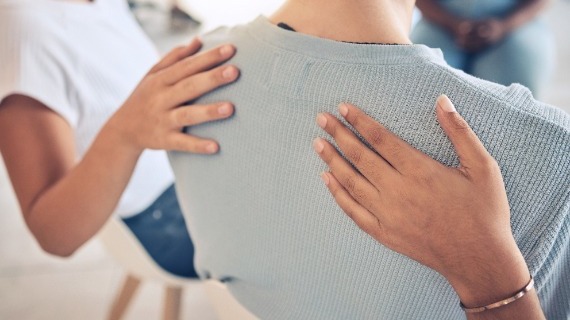 2 people having their hands on the back of a third individual