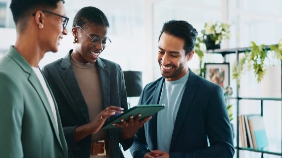 3 individuals standing around while studying an ipad