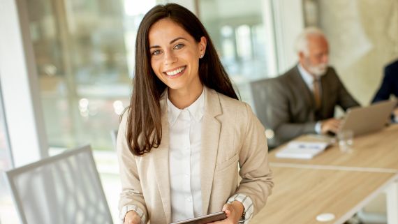 A women sitting on the edge of a conference table with 3 men in the background