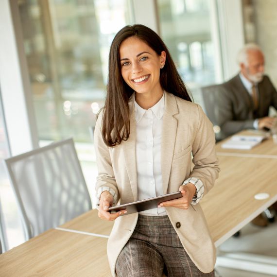 A women sitting on the edge of a conference table with 3 men in the back