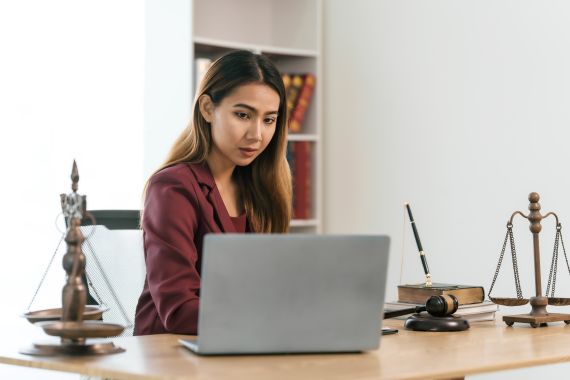 A women sitting at a desk while working on a laptop