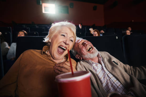An older couple laughing while watching a movie