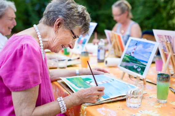 4 Older Individuals sitting around a table painting 