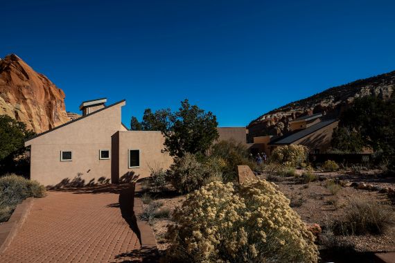 A small home sitting in the desert at the bottom of a canyon