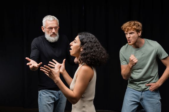 1 older man, a younger women, and a young man all acting in exagerated ways