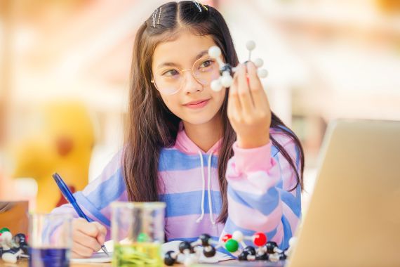 A young girl looking at a model of a molecule