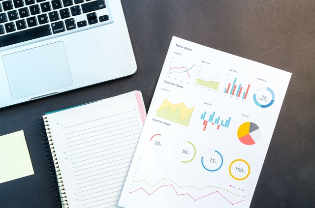 laptop sitting next to charts and graphs