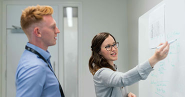 two people writing on a whiteboard