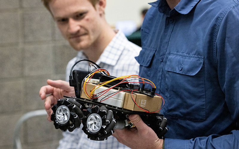 student holding a small robotic car