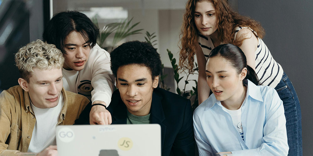 group of people sitting around a laptop