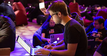 student working on a laptop in a large group