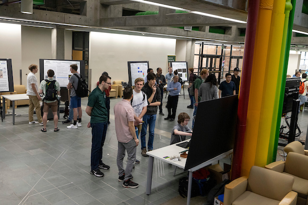wide shot of students browsing several tables with projects