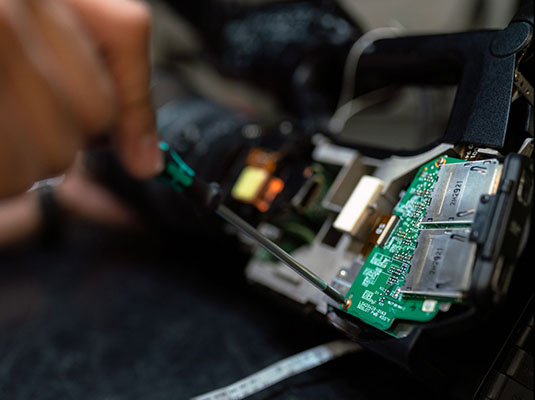 hand using a screwdriver on a piece of computer hardware