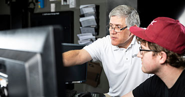 man assisting another man at a computer