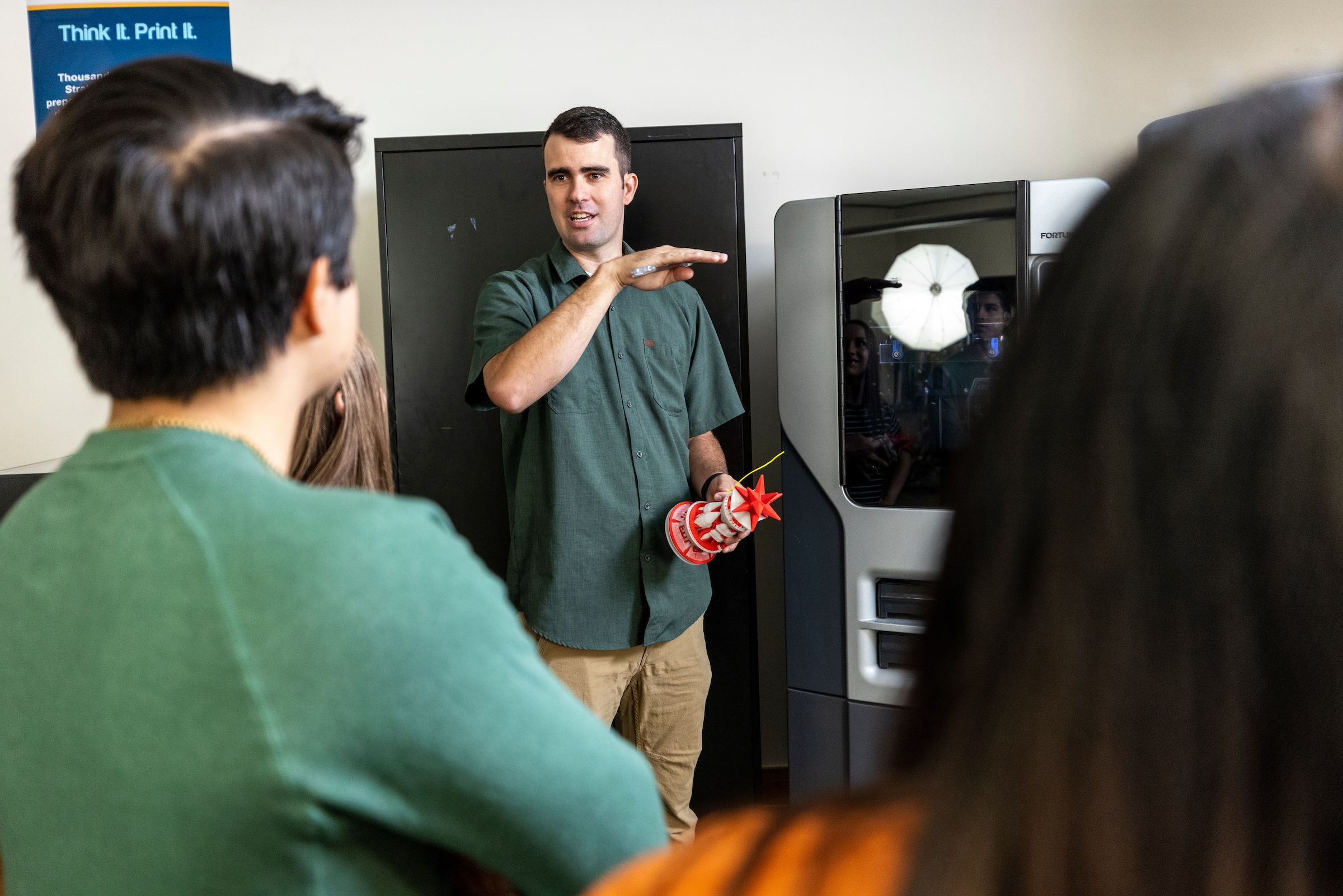 a man standing next to a 3D printer talking