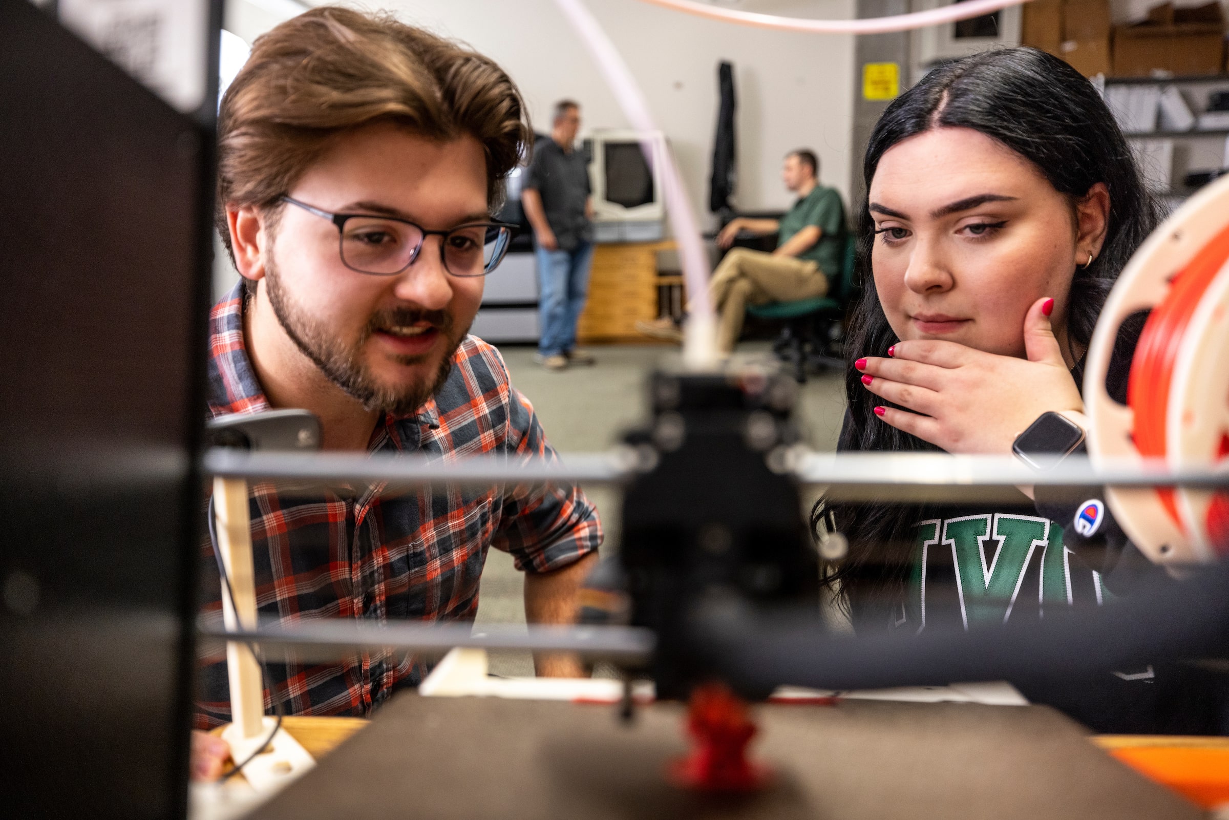 Students looking at a 3d printer printing something