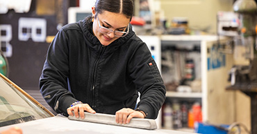 woman sanding a car hood