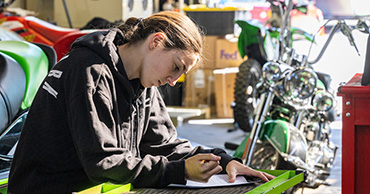 woman working on paperwork with motorcycles in the background