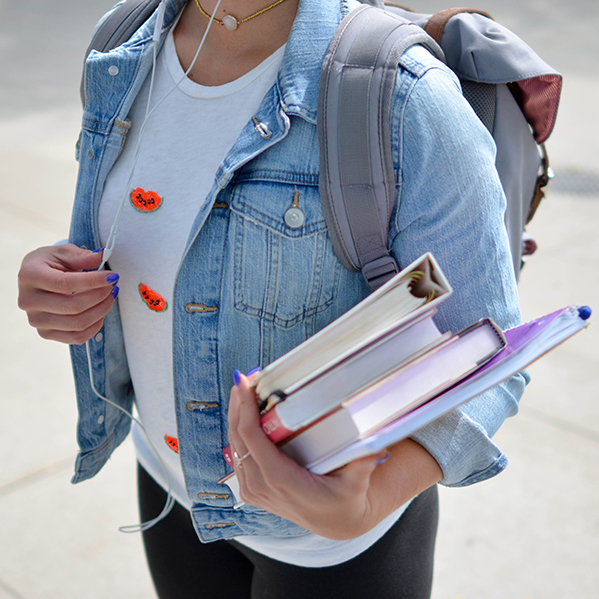 student carring backpack and books