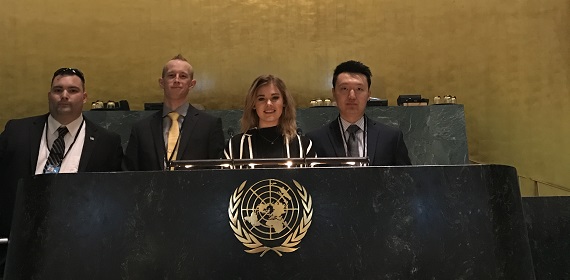 four students standing behind a lectern with a globe embossed on it