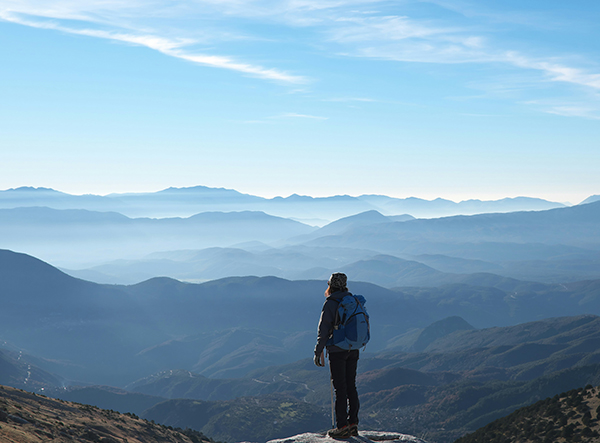 Hiker looking over the peaks of mountains from a summit