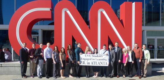 a large group of students holding a sign, standing in front of giant red CNN letters