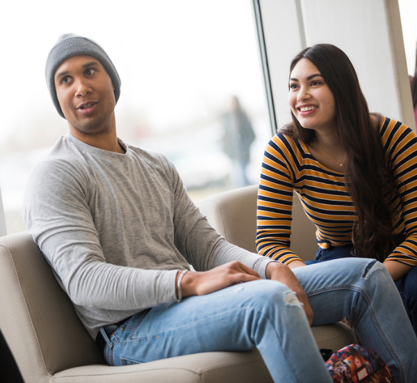 Two students smiling and interacting with someone out of view