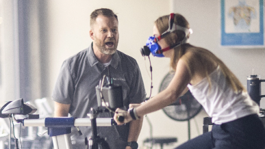 Person riding a stationary bike with a oxygen mask on