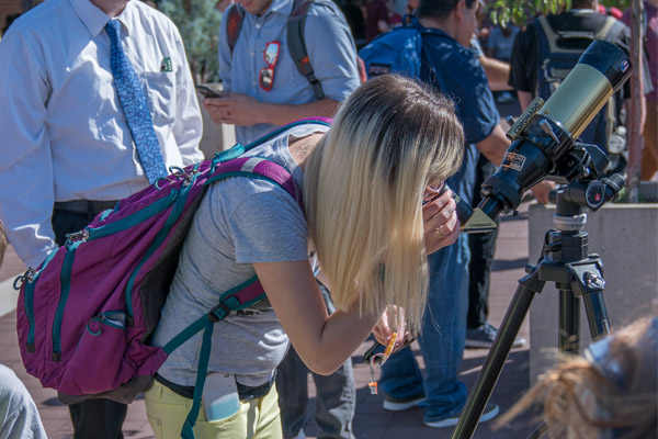 woman looking through telescope