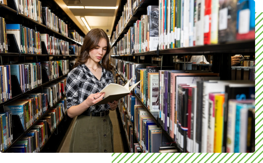 student reading a textbook in a library