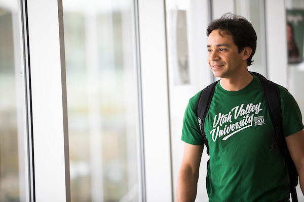 Student wearing green UVU shirt looking out window.