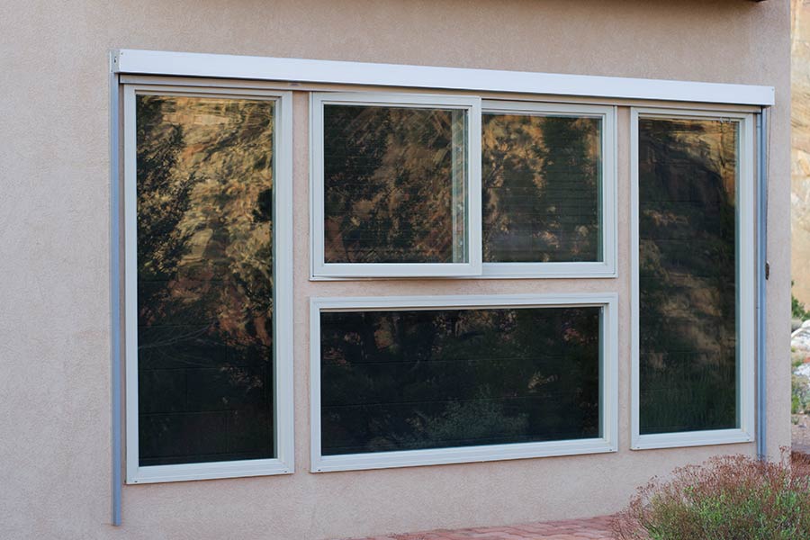 Photo of a trombe wall. A wall painted black that sits a few inches behind a window.