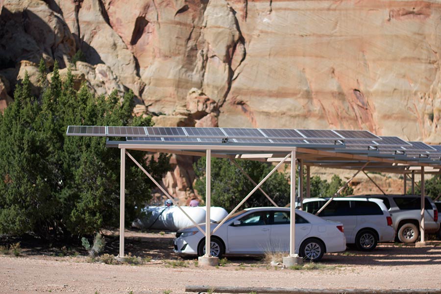 Cars sitting underneath raised solar panels.