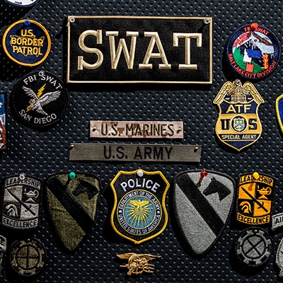 SWAT, FBI, ATF, Army, Marines, US Border patrol Patches pinned to the wall.