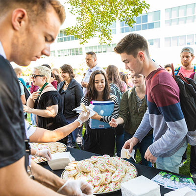 Students gathered in a crowd around a table covered with cookies