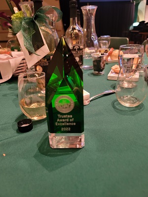 Green crystal award on table with green tablecloth and dinner ware in background