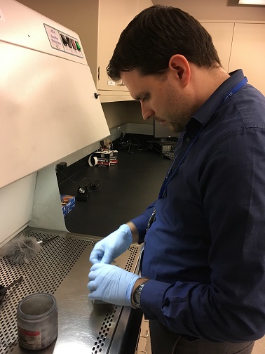 Benjamin Little at work in the lab wearing blue gloves