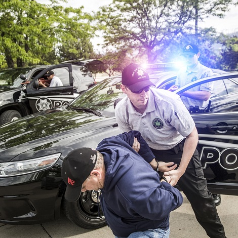 A police officer in training pratices an arrest move on an older gentlemen