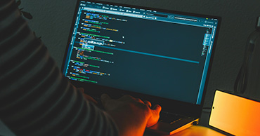 man typing code on a laptop with a blue screen