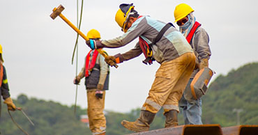 men in construction vests and hats working on a roof