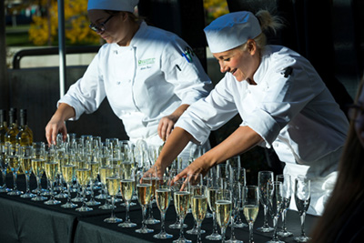 students arranging filled glasses at gala