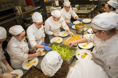Group of culinary students around a table preparing dishes