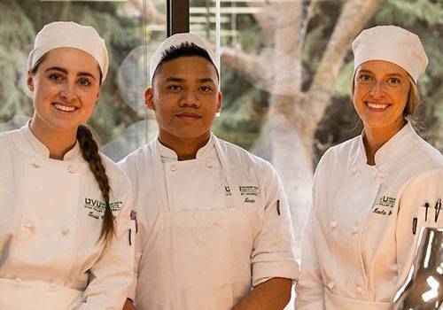 three students in chef uniforms