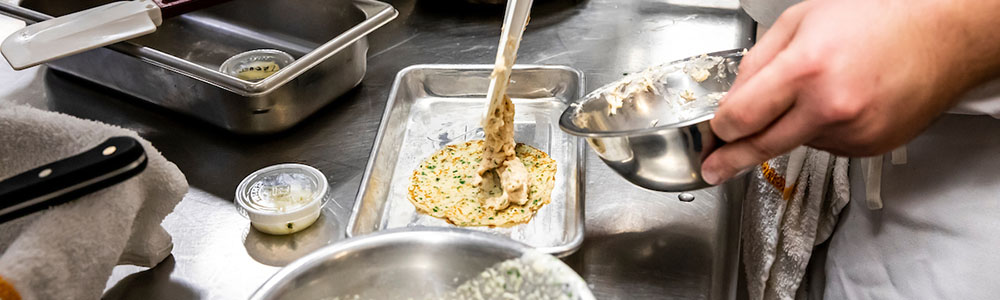 chef spooning food onto a plate