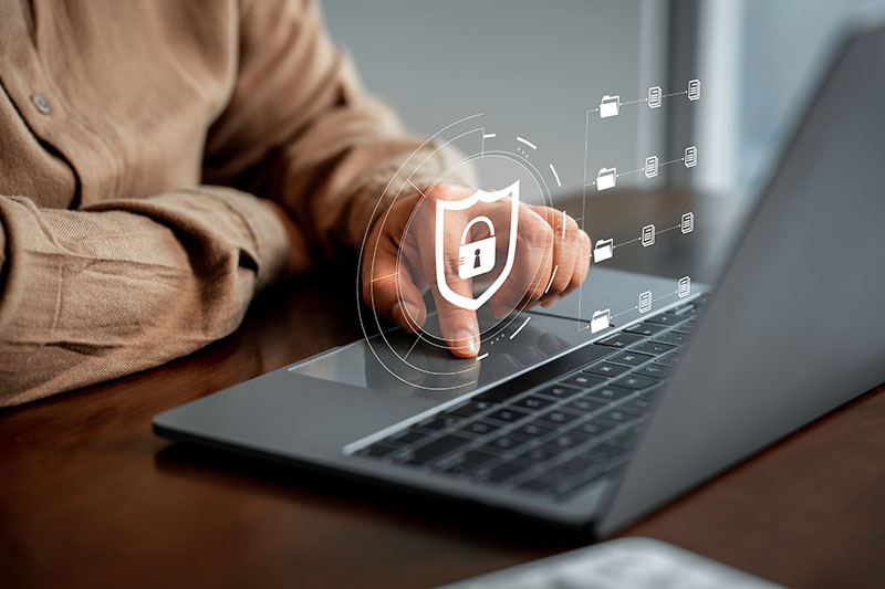 B.S. in Cybersecurity person working on laptop with padlock icon overlayed