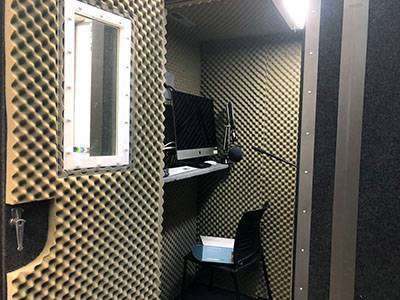 Interior of a isolation booth for voice over work with computer, microphone, and chair